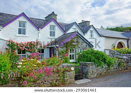 A beautiful row of Irish country Cottages and gardens in summer with blue sky and clouds, in the heart of The Ring of Kerry, Ireland