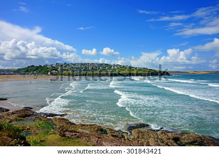 The Cornish beach at Polzeath, North Cornwall, surfers and bathers enjoying the surf and Sea with blue sky and white clouds in Summer time, United Kingdom