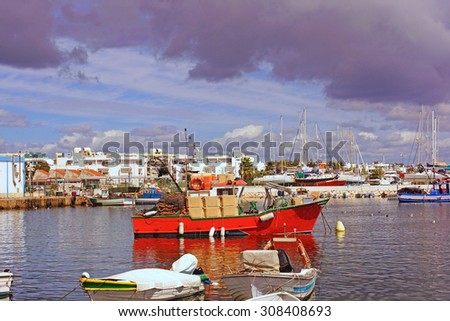 A laden cargo boat at anchor waiting to go to sea on a busy summer day in the historical fishing harbor of Lagos, The Algarve, Portugal