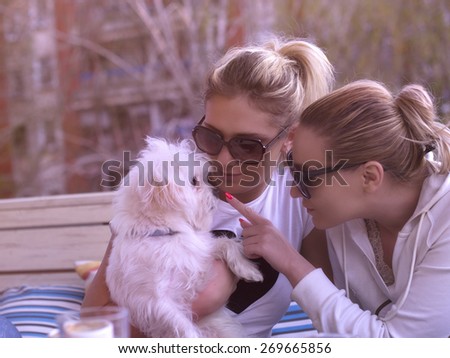 Two girls with their dog in coffee house enjoying on the sun