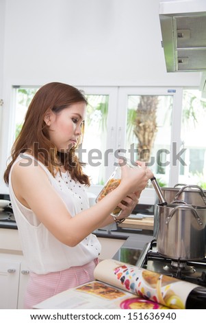 A woman opening her pasta bottle in front of the stove.