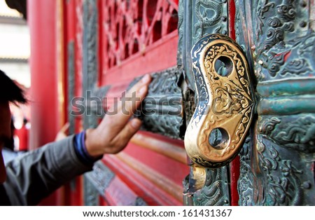 Golden key in the door of a Chinese temple.  The believer touches the sacred door of Chinese temple according to ancient tradition. Canon 5D.