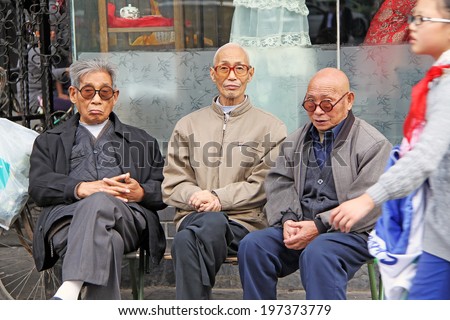 XIAN, CHINA - OCTOBER 13, 2009: elderly men and young pioneer on the one of the main streets of Xian city,China on October 13,2009. China pioneers consist of children between ages of six and fourteen.