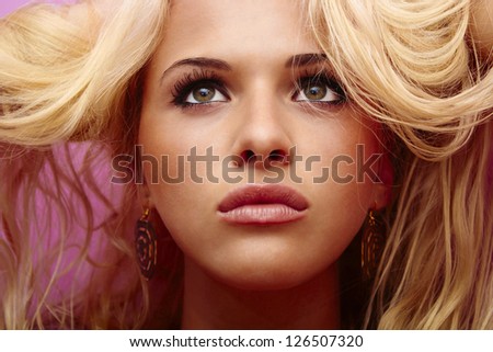 Beautiful blond woman with curly hair. pink background