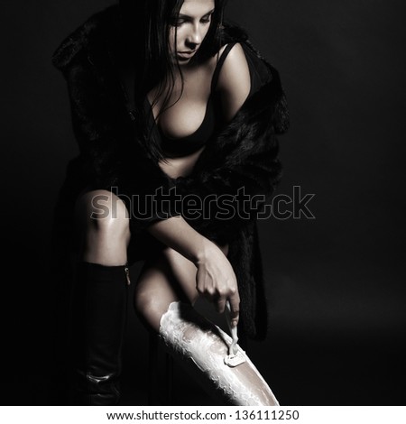 beautiful brunette woman shaves her legs