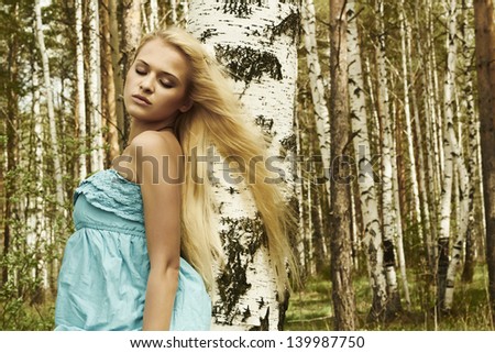 Beautiful blond woman in russian forest. hair flying in the wind