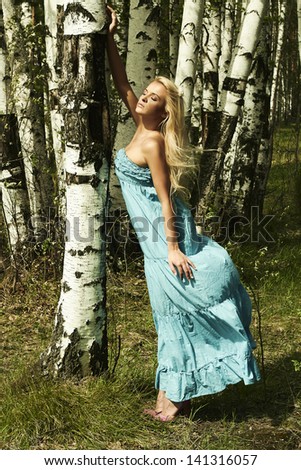 Beautiful blond woman in summer forest. flying dress