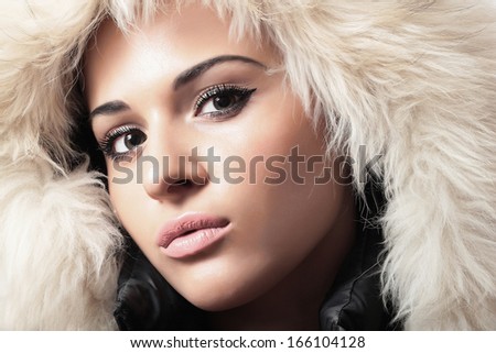Fashion portrait of young beautiful woman with fur. white fur hood. winter style. make-up