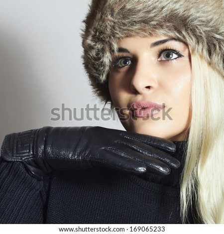 Beauty Fashion blond Girl in Fur Hat. Beautiful Blond Woman in Leather Gloves. Black sweater. Winter Fashion