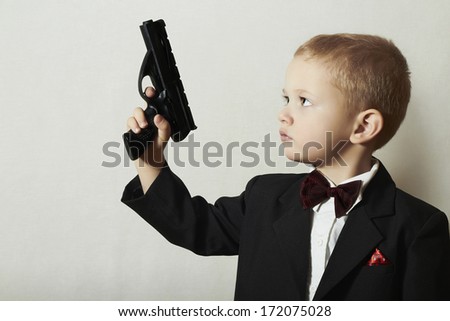 Little James Bond. Fashionable Little Boy in Bow tie.Stylish Agent. Fashion Children. 4 Years Old Child in Black Suit. Elegance Handsome Boy with Gun.