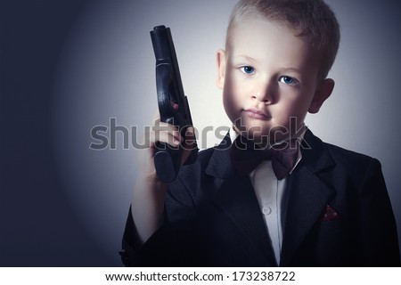 Handsome Boy with Gun.Fashionable Boy in Suit .Stylish Agent. Fashion Children.Child in Bow tie. Elegance. Little James Bond