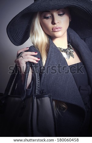 Beautiful Blond Woman in Black Hat. Fashionable Lady in Topcoat. Elegance Beauty Girl with Handbag. Spring Shopping