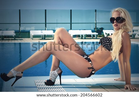 beautiful blond woman in sunglasses near the swimming pool.summer girl in bikini.blond sexy woman in high heels.