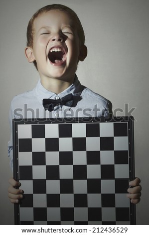 Funny Little boy with chessboard.Children Emotion.Smile.laughter