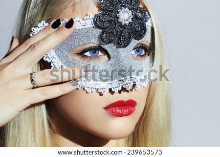 Beautiful Blond Young Woman in Carnival Mask.Masquerade. Beauty Girl with red lips. Manicure.Close-up portrait