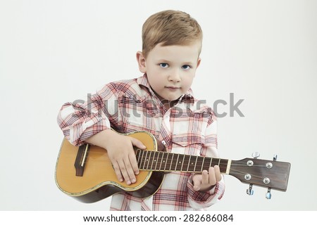 funny child boy with guitar.ukulele guitar. fashionable country boy playing music