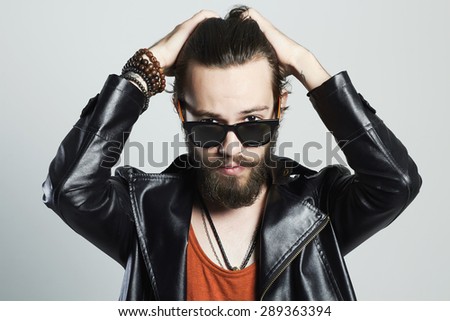 fashion Portrait of young bearded man in leather jacket. Hipster in sunglasses.haircare