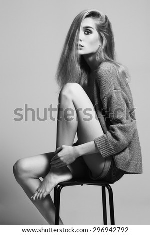 fashion monochrome portrait of Lovely blond woman sitting on a stool. beautiful girl