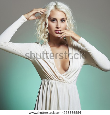 Fashion portrait of young beautiful woman. Sexy decollete blonde. Blond girl. Curly hairstyle.green background