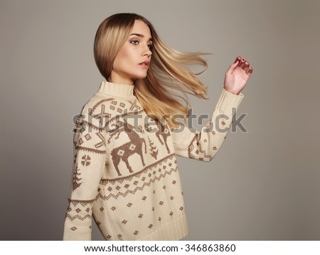 Beautiful Woman with flying hair in winter pullover. Beauty Blond Girl. Healthy hair