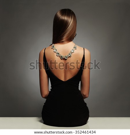 beautiful back of young woman in a black sexy dress.luxury.beauty brunette sitting girl Girl with a necklace on her back.Elegant fashion glamor photo