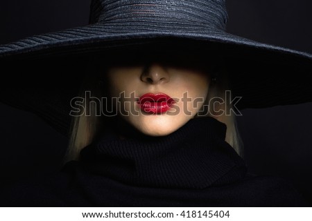 Beautiful woman in hat. Retro fashion.summer hat with large brim over dark background