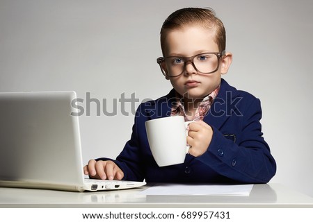 Young business boy with computer. funny child in glasses. little boss in office