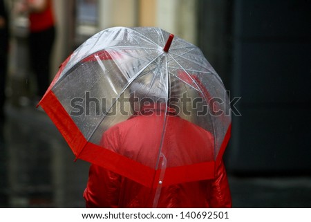 woman with umbrella walking in rain rush hour