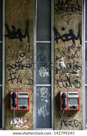 two telephones on the wall covered with graffiti