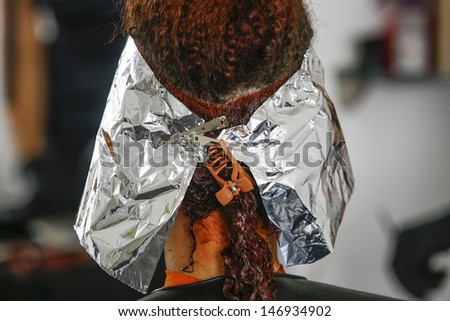 Close-up of the head of a woman in the process of getting her hair dyed by her beautician
