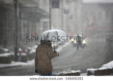 Man with umbrella during snow storm in the street