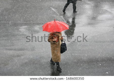 Girl with umbrella during snow storm in the street