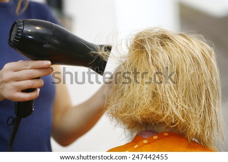 Hairstylist Drying Hair Blonde in Salon for short hair
