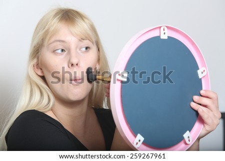 woman as applying makeup near a small mirror