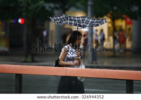 Belgrade, Serbia - Jun 30, 2014: Girl holding an umbrella that the wind turned. People in the town during heavy rain. Walking with an umbrella on June in Belgrade, Serbia.