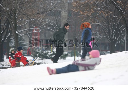 Belgrade, Serbia, January 03, 2011: Parents with kids playing on snow, people and family with kids having fun on snowy small mountain during the winter in Belgrade