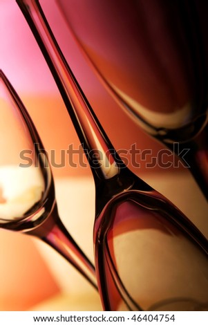 Three beautiful wine glasses in front of colorful background with shades of yellow, orange, pink and red.