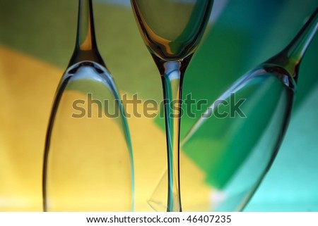 Three beautiful wine glasses with blue, yellow and green lighted background
