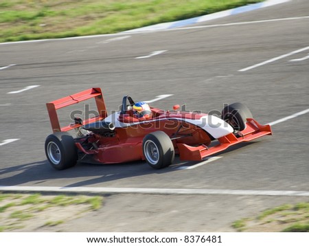 Red racing formula car in a cirquit race, all brands removed