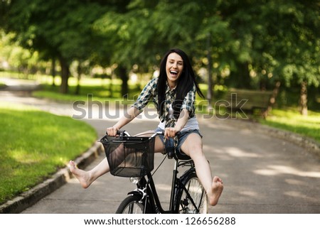 Happy young woman cycling through the park