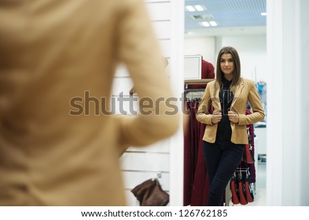 Beautiful Young Woman Trying On Jacket In Front Of Mirror