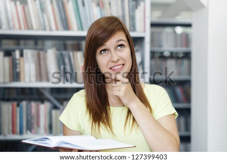 Young woman day dreaming in library