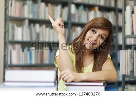 Beautiful student pointing at copy space