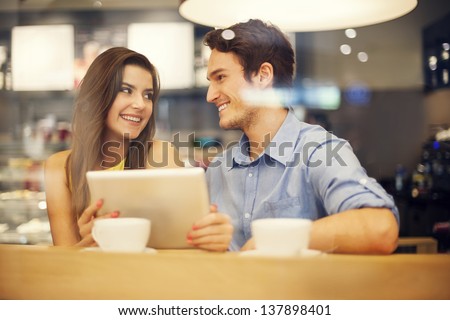 Flirting Couple In Cafe Using Digital Tablet