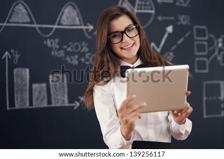 Smiling  teacher using digital tablet in classroom