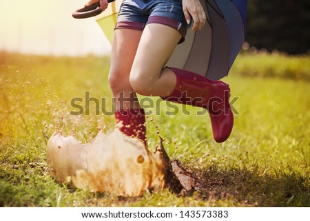 Jumping woman with umbrella and rubber boots
