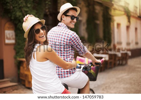 Happy Couple Riding A Bicycle In The City Street