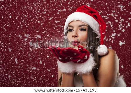 Beautiful santa claus woman blowing snowflakes