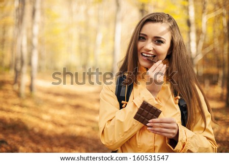 Happy young hiker woman eating chocolate