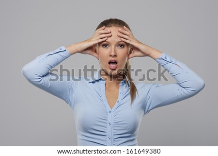 Confused and shocked businesswoman holding hands on head